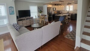 A spacious living area with a sofa, a TV, and a dining table. - Memory Lane with Community Pool! (Laconia)