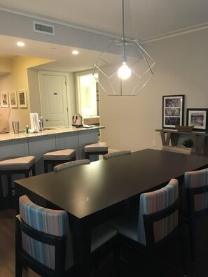 Enjoy meals in this stylish dining area with a dark table and six chairs, surrounded by framed pictures and a unique pendant light.