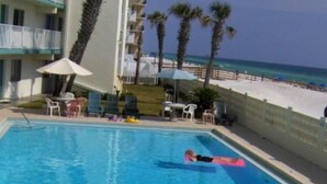 A swimming pool with a person floating on a green float. - Pet friendly on the beach with private balcony! (Fort Walton Beach)
