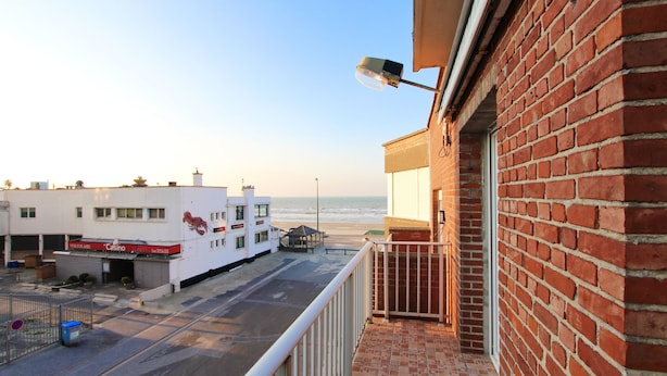 A balcony with a view of the beach and ocean.