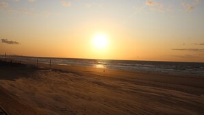 A beach with a wooden boardwalk and the ocean in the background.