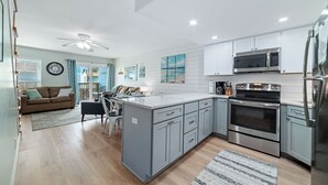 A modern kitchen with grey cabinets, stainless steel appliances, and a central island.