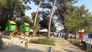Un parque con juegos infantiles, zonas de descanso y vista al agua.