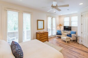 A bedroom with a bed, dresser, and a TV area with seating.