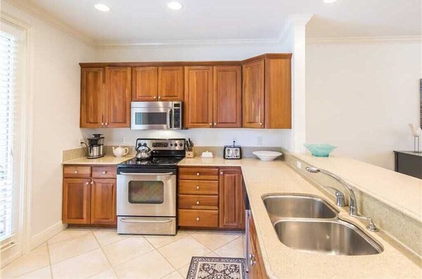 A kitchen with wooden cabinets, stainless steel appliances, and a double sink. - Gulf Place, Shops, Restaurants, Community Pool, Beach Access, New to Program (Santa Rosa Beach)