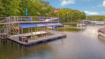 A dock with a covered seating area, a flag, and a boat.