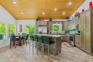 Una cocina moderna con techo de madera, taburetes de bar y una mesa de comedor.