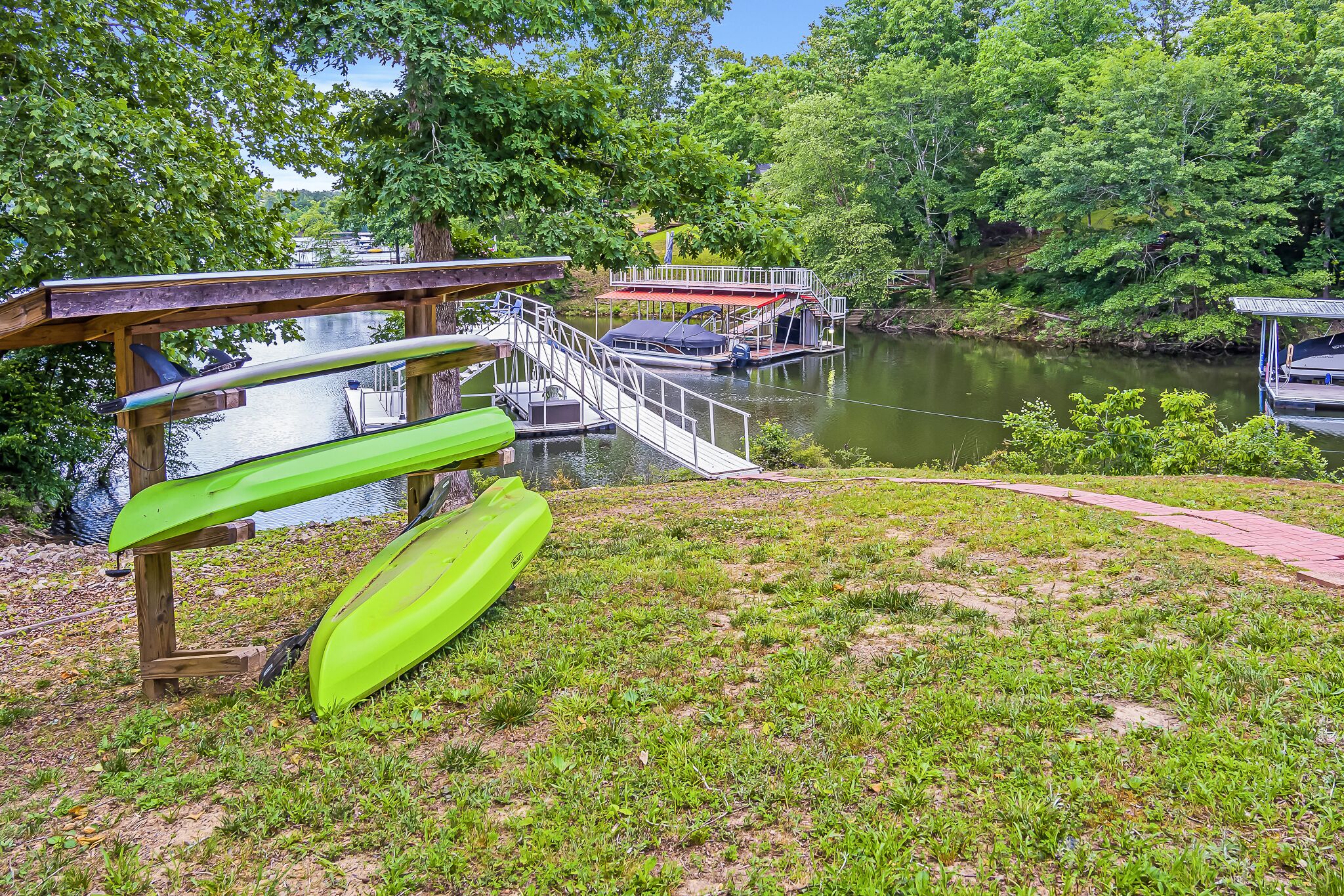 A riverside park with a wooden deck, a kayak, and a small boat dock.