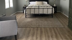 A bedroom with a bed, a ceiling fan, two bedside lamps, a nightstand, a dresser, and a window with blinds.