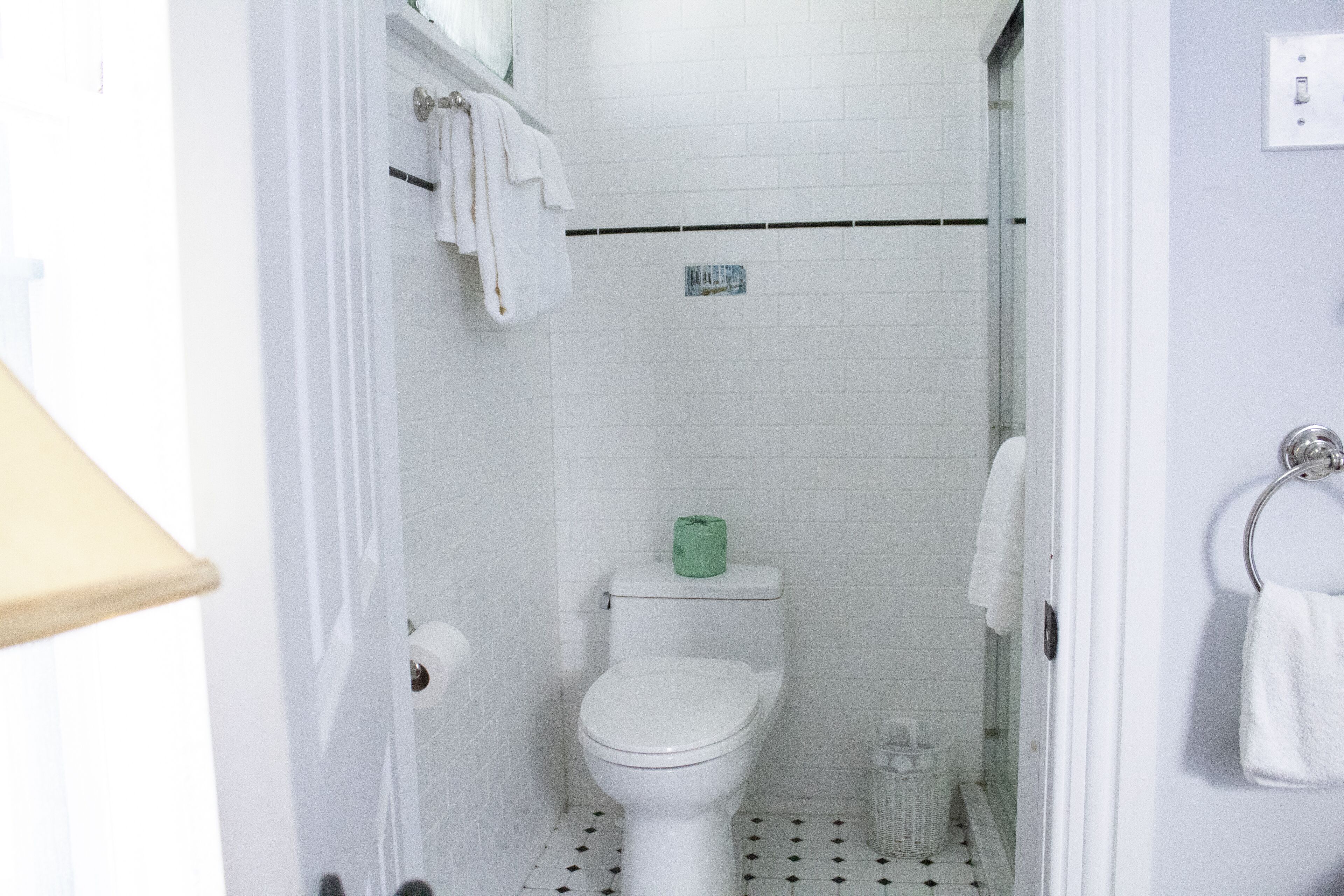 Un baño con inodoro blanco, cabina de ducha con vidrio y piso de baldosas.
