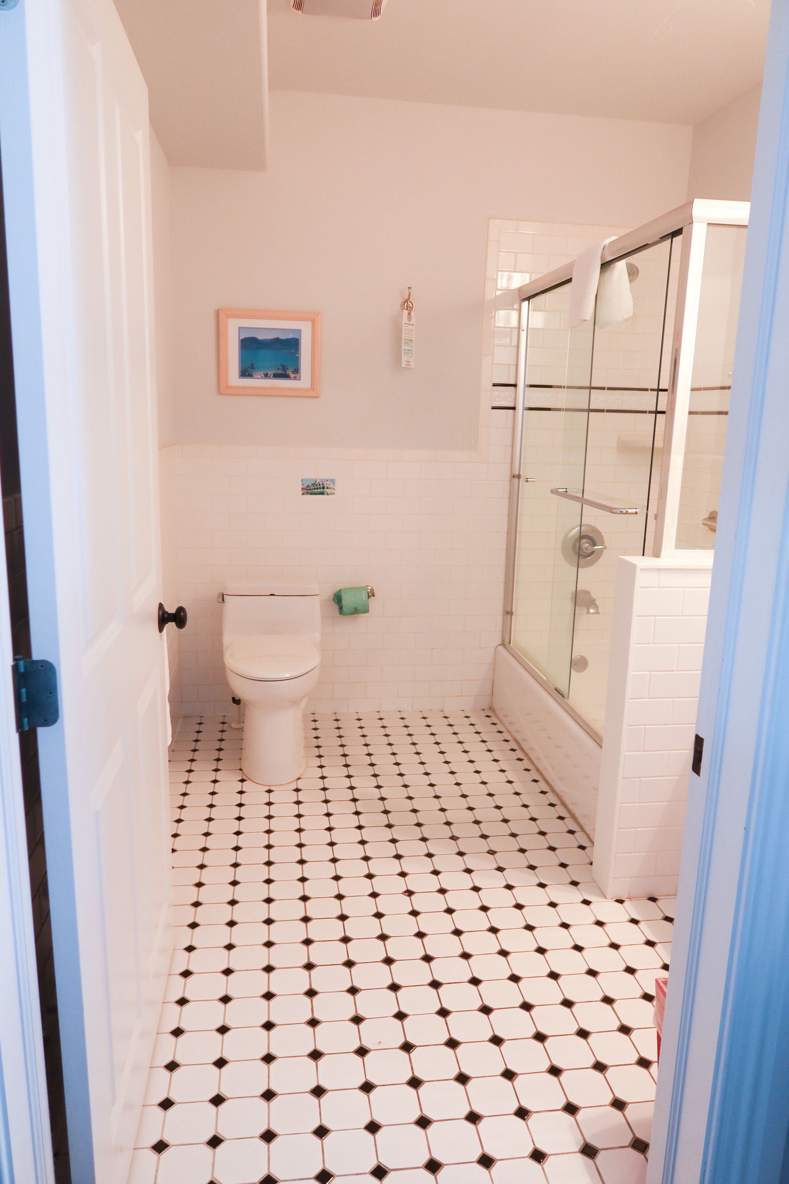Un baño con inodoro, cabina de ducha de vidrio y suelo de baldosas.