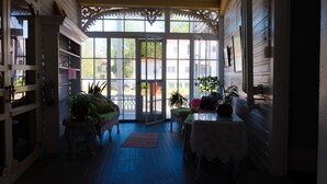 A sunlit room with a large window, wooden floors, and a variety of potted plants.