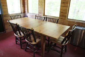 Un tavolo da pranzo in legno con sei sedie, ampie finestre ed un elettrodomestico in acciaio.