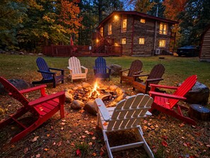 A cabin with a fire pit surrounded by Adirondack chairs. - Unique Rustic Ski/Tree House - Game room, Hot tub & Sauna (Jay)
