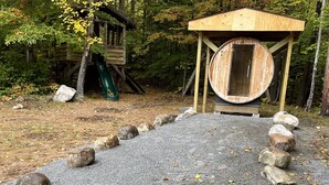 Una estructura de madera con un ventanal circular y techo de madera, rodeada por un sendero de grava y rocas.