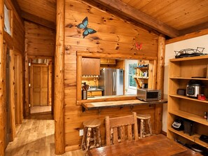 A wooden cabin interior with a kitchen area, including a refrigerator, microwave, and wooden shelves. - Unique Rustic Ski/Tree House - Game room, Hot tub & Sauna (Jay)