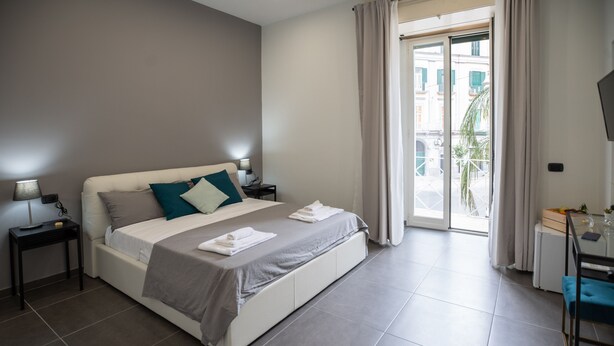 Habitación de hotel moderna con una cama grande, un escritorio y vista a la calle por la ventana.