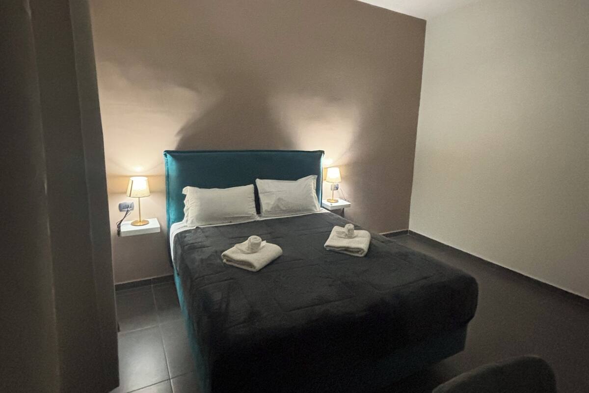 A modern hotel room with a single bed, two bedside lamps, and a small table.