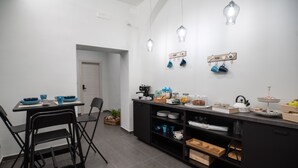 Una cocina moderna con gabinetes negros, una mesa de comedor con sillas y lámparas colgantes.