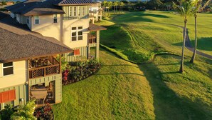 Une maison à plusieurs étages avec un balcon, une pelouse bien entretenue et un terrain de golf en arrière-plan.