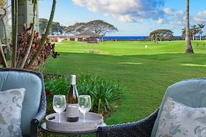 Relax and socialize in this serene outdoor seating area overlooking a lush golf course and the ocean.