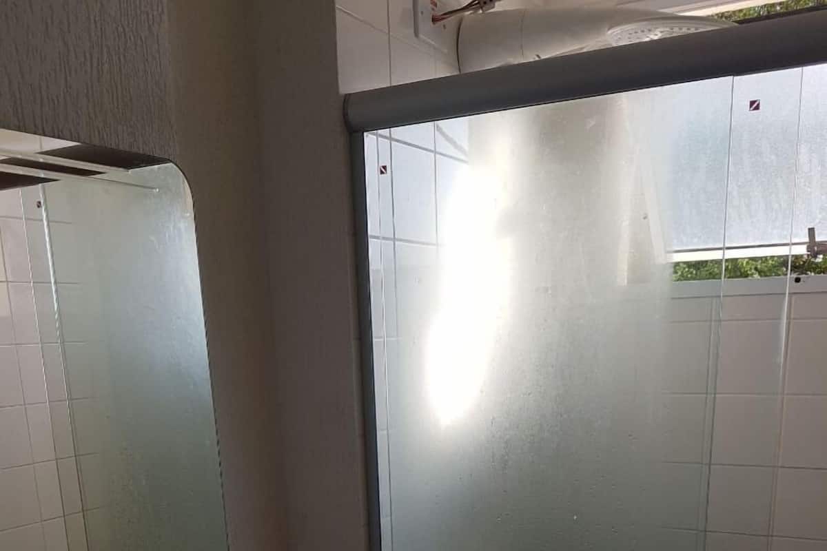 Ein Badezimmer mit Granitwaschtisch, Spiegel und einer Duschkabine aus Glas.