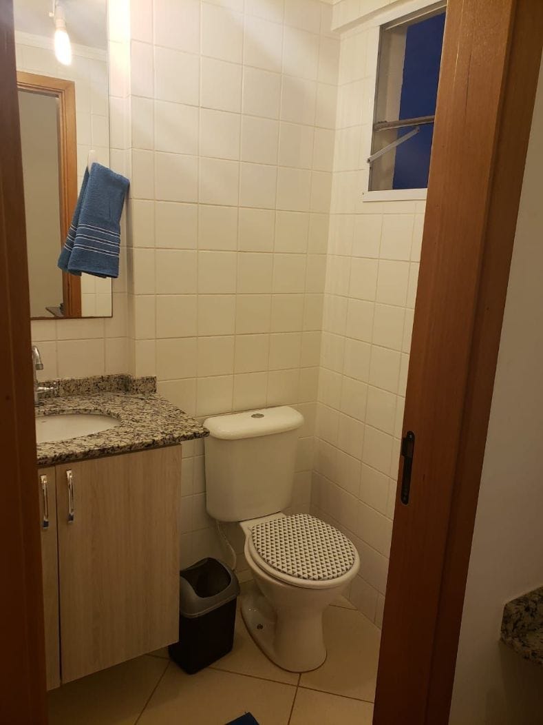 A small bathroom with a toilet, sink, and a mirror.