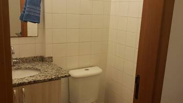 A small bathroom with a toilet, sink, and a mirror.