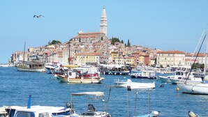Un porticciolo con barche, un'imponente torre e edifici colorati sullo sfondo.