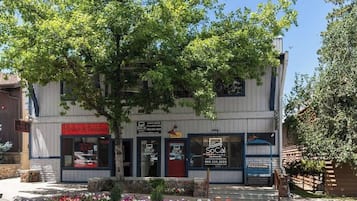 Ein zweistöckiges Gebäude mit Schaufenster, einem Schild für 'SoCal Vacation Rentals' und einem Baum davor.