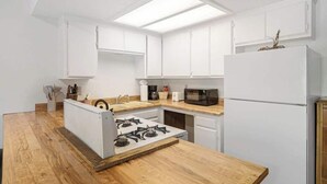 Eine moderne Küche mit weißen Schränken, einer Mikrowelle, einem Herd und einem Kühlschrank.