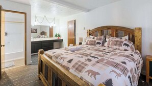 A bedroom with a wooden bed, a bedside table, a nightstand, a dresser, and a mirror. - Teddy Bear, Perfect Location in the Village (Big Bear Lake)