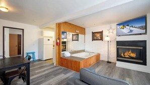 A modern room with a wooden bathtub, a fireplace, a dining area, and a kitchen. - Polar Bear, Perfect Location, hot tub (Big Bear Lake)