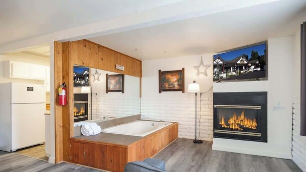 A modern room with a wooden bathtub, a fireplace, and a view of a building. - Polar Bear, Perfect Location, hot tub (Big Bear Lake)