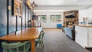 Ein Essbereich mit Holztisch und -stühlen, einem Steinofen und einem an der Wand befestigten Fernseher.