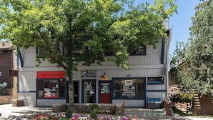 Ein zweistöckiges Gebäude mit Schaufenster, einem Schild für 'SoCal Vacation Rentals' und einem Baum davor.