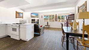 A modern kitchen with white appliances, a dining area with a wooden table and chairs, and a view through large windows. - Grizzly Bear, Perfect Location in the Village (Big Bear Lake)