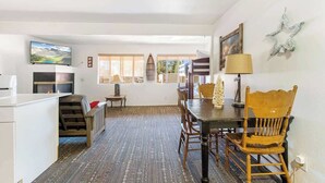 A dining area with a table, chairs, and a television mounted on the wall. - Grizzly Bear, Perfect Location in the Village (Big Bear Lake)