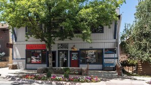 A two-story building with a storefront, a sign for 'SoCal Vacation Rentals,' and a tree in front. - American Black Bear. Perfect Location (Big Bear Lake)