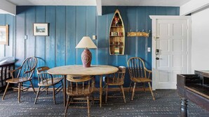 A room with a round wooden table, four wooden chairs, a lamp, a bookshelf, and a white door. - American Black Bear. Perfect Location (Big Bear Lake)