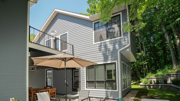 Een modern huis met een patio, compleet met een tafel, stoelen en een parasol.