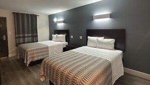 A hotel room with two beds, dark walls, and a modern design.