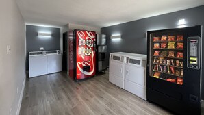 A laundry room with a Coca-Cola vending machine, a coffee machine, and a snack vending machine.