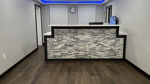 A reception area with a stone-textured counter, recessed lighting, and a clock on the wall.