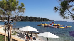 Une plage équipée de jeux d’eau gonflables, de parasols et de chaises longues.