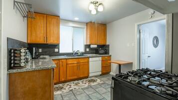 A kitchen with wooden cabinets, a gas stove, a dishwasher, and a granite countertop.