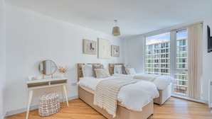 A bedroom with a large bed, a bedside table, a mirror, and artwork on the wall.