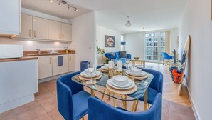 A modern kitchen with white cabinets and a dining area with blue chairs and a glass table set for six.