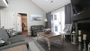A living room with a sofa, a coffee table, a fireplace, and a view of the outdoors. - Parkview Bay, 3 bed, 3 bath, lakeview, elevator, wifi, pool (Osage Beach)