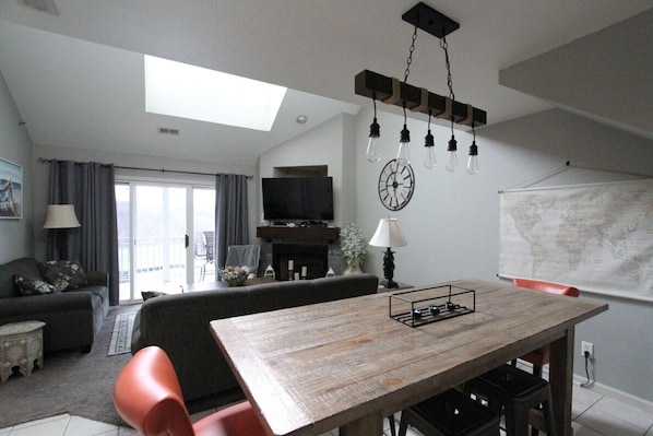 Una sala de estar con una mesa de comedor de madera, un sofá, un televisor y un mapa mundial en la pared.